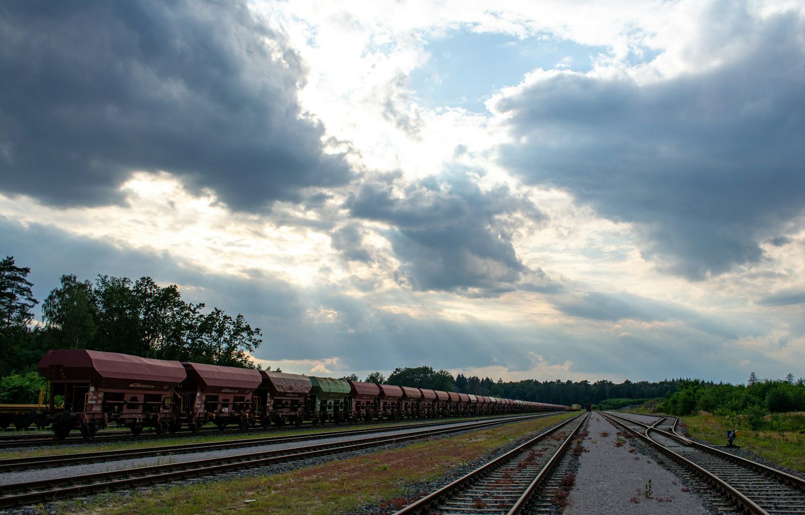 a train traveling down train tracks under a cloudy sky