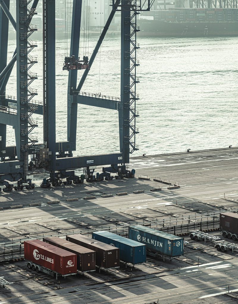 blue and red cargo containers near body of water during daytime